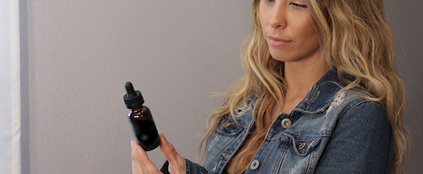 Frau mit THC-Öl Flasche in der Hand